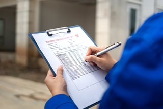 A construction foreman is checking on building quality checklist report during inspecting at the house construction site